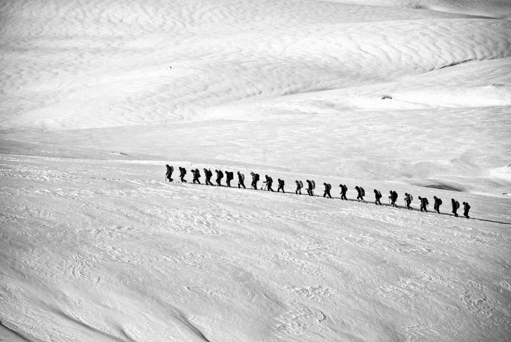 people walking on snow field grayscale photography